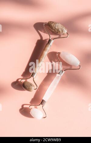 Deux rouleaux de jade en pierre sur fond rose. Rouleaux de quartz, anti-rides, soin de beauté de relaxation pour la peau. Outil de beauté tendance pour l'auto-soin. Plat Banque D'Images