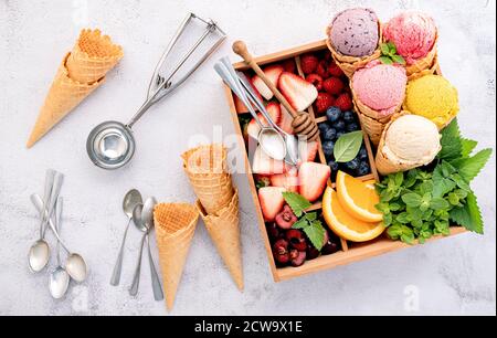 Divers de saveur de crème glacée dans des cônes avec des baies en boîte de bois sur fond de béton . Concept de menu été et sucré. Banque D'Images
