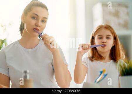 Bonne famille ! La mère et la fille de l'enfant fille se brossent les dents brosses à dents dans la salle de bains. Banque D'Images