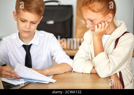 adorable redhead enfant fille soutient petit ami garçon travaillant sur ordinateur portable, elle est à l'écoute de ses problèmes au travail, les délais. à la maison Banque D'Images