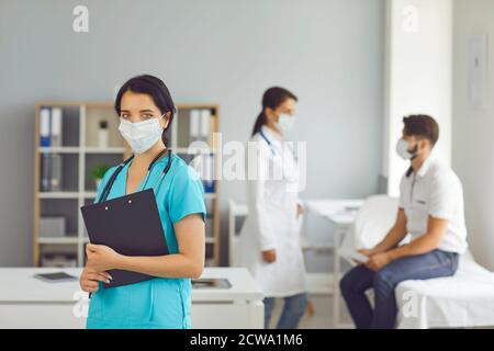 Femme médecin debout au-dessus de l'infirmière et homme patient parlant arrière-plan Banque D'Images