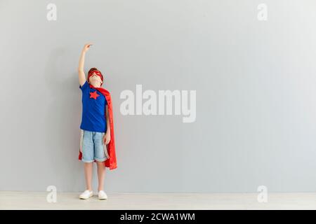 Garçon souriant en costume de super-héros debout et se lever à la main Banque D'Images