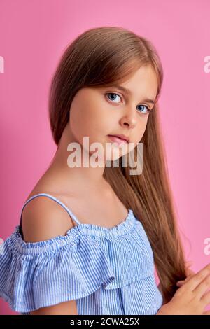 portrait d'une fille modèle caucasienne sérieuse posant à l'appareil photo isolé sur fond rose. jeune adolescent en robe d'été regarder l'appareil photo Banque D'Images