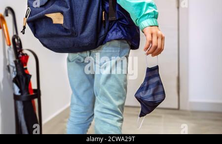 Garçon méconnaissable avec sac à dos tenant le masque à la main Banque D'Images