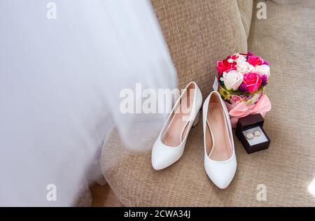 Composition des détails du matin de la mariée. Vue de dessus des anneaux de mariage, beau bouquet de fleurs roses et chaussures en cuir. Banque D'Images