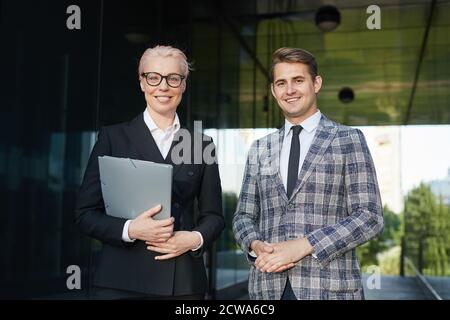 Portrait d'un couple professionnel qui a réussi en souriant à l'appareil photo tout en étant debout ensemble à l'extérieur Banque D'Images