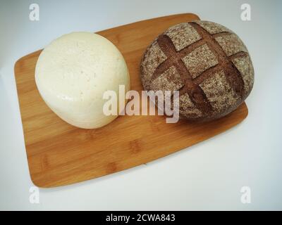 Tête ronde de fromage avec du pain rustique sur un plateau en bois Banque D'Images