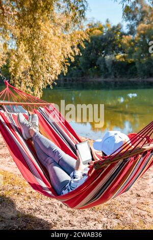 femme lisant un livre sur un hamac à l'extérieur, sur la plage de la rivière Banque D'Images
