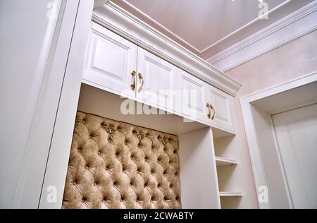 armoire blanche classique avec sièges et étagères dans un couloir lumineux contemporain. Mobilier classique. Banc de l'armoire du coupleur de chariot Banque D'Images