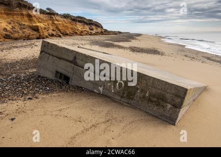 La deuxième Guerre mondiale pilbox qui était autrefois sur le sommet de la falaise et maintenant due à l'érosion côtière est sur la plage en dessous, Benacre, Suffolk, Angleterre. Banque D'Images