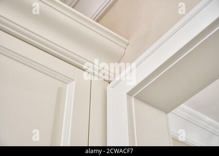 Détail de la garde-robe blanche classique avec sièges et étagères dans le couloir lumineux contemporain. Mobilier classique Banque D'Images