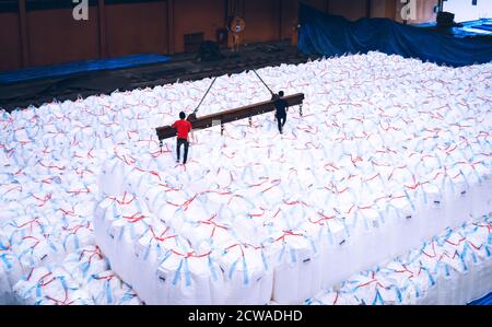 Un pont roulant lève les sacs géants de tapioca à l'aide d'une barre de répartition dans l'entrepôt de stockage. Chargement en vrac dans un équipement de manutention de sacs jumbo. Banque D'Images