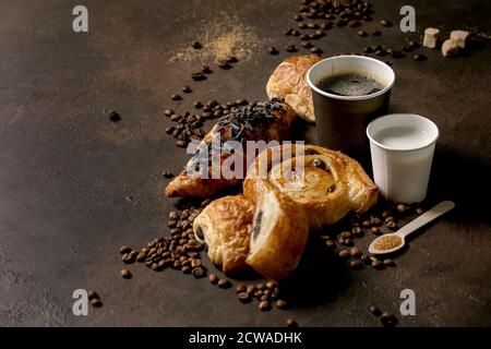 Variété de pains à base de raisins secs et de chocolat, croissant avec tasses de café americano et de lait, grains de café, bois recyclé Banque D'Images
