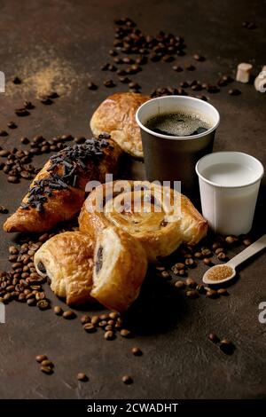 Variété de pains à base de raisins secs et de chocolat, croissant avec tasses de café americano et de lait, grains de café, bois recyclé Banque D'Images