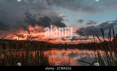 Ciel sur feu au-dessus du lac Westport à Stoke on Trent, Staffordshire, Royaume-Uni.scène colorée de coucher de soleil avec ciel spectaculaire. Banque D'Images