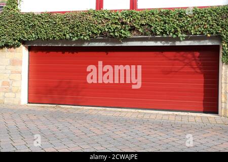 Porte de garage rouge de haute qualité (porte en coupe) à côté d'un bâtiment résidentiel Banque D'Images