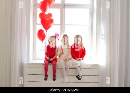 Trois belles petites filles s'assoient avec des balles rouges festival Banque D'Images