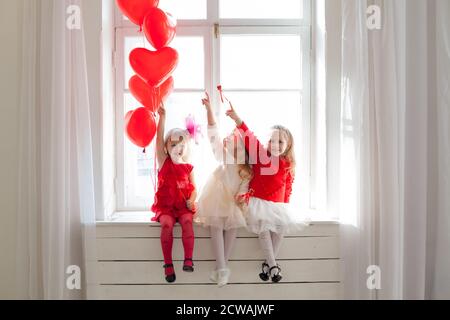 Trois belles petites filles s'assoient avec des balles rouges festival Banque D'Images