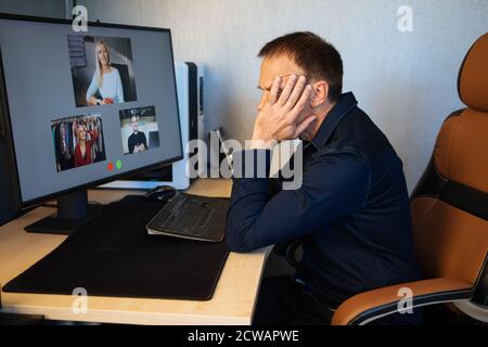 Homme d'affaires fatigué dormant sur son bureau tout en ayant un appel vidéo via un ordinateur dans le bureau à domicile. Réunion d'équipe à distance, vidéo, conférence en ligne Banque D'Images