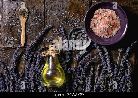 Concept SPA. Plat de fleurs de lavande fraîches et sèches, huile essentielle, sel rose, sur carreaux de céramique brun foncé. Banque D'Images