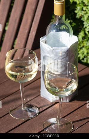 Deux verres à vin à l'extérieur avec une bouteille de vin blanc dans un manchon de refroidisseur Banque D'Images