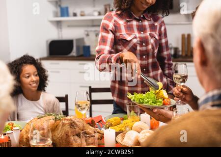 femme afro-américaine mettant des légumes à l'assiette pendant le dîner d'action de grâce Banque D'Images