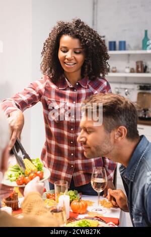 foyer sélectif de l'homme avec les yeux fermés près d'afro-américain femme prenant du maïs pendant le dîner d'action de grâce Banque D'Images