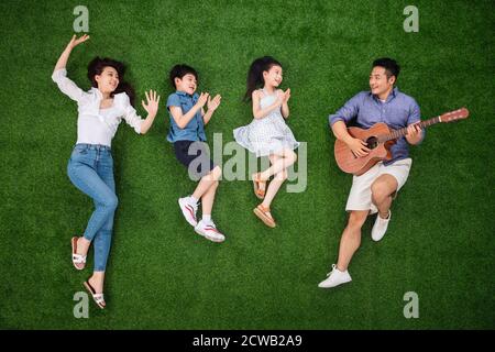 Le bonheur d'une famille de quatre chantant sur le herbe Banque D'Images