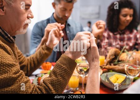 objectif sélectif de l'homme âgé qui tient les mains d'une famille multiculturelle sur action de grâce Banque D'Images