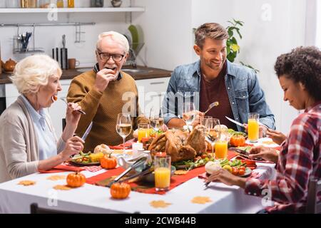 Foyer sélectif de la famille multiculturelle avec la fille célébrant l'action de grâce près plats savoureux sur table Banque D'Images