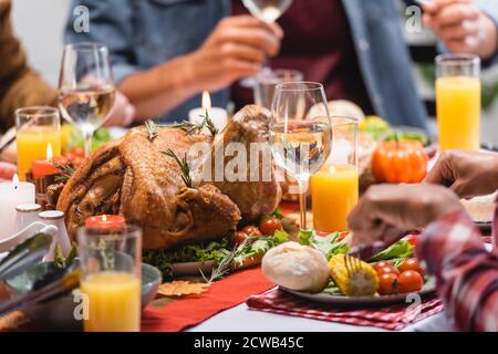 Vue sur la dinde avec boissons et bougies sur la table famille quasi-multiethnique célébrant l'action de grâce Banque D'Images