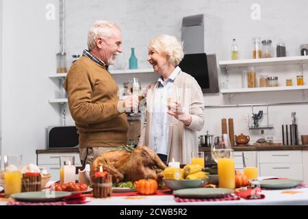 Objectif sélectif de couple âgé avec un verre de vin célébrant thanksgiving près de la nourriture sur table Banque D'Images