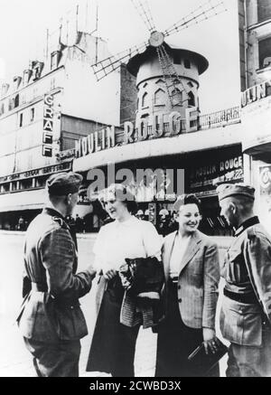 Des soldats allemands discutant avec des femmes françaises à l'extérieur du Moulin Rouge, à Paris occupé, juin 1940. Le photographe est inconnu. Banque D'Images