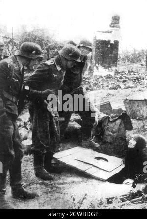 Troupes allemandes entrant à Stalingrad, Russie, septembre 1942. Une femme russe âgée émerge d'une cave dans les ruines brisées de la ville. Entre août 1942 et février 1943, la bataille de Stalingrad a vu 750,000 soldats russes tués, blessés ou capturés et plus de 40,000 civils ont perdu la vie. Du côté de l'axe, 740,000 ont été tués ou blessés et 110,000 ont été faits prisonniers. La défaite de Stalingrad a été un revers dont l’Allemagne nazie a finalement été incapable de se remettre. Le photographe est inconnu. Banque D'Images