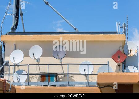 Groupe d'antennes paraboliques blanches rondes sur un toit de condominium. Banque D'Images