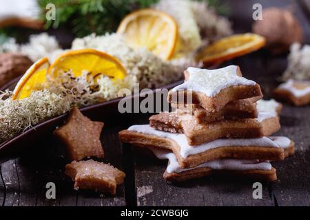 Vitrage formes cookies de Noël étoiles avec arbre de Noël, Moss et sec en orange en tranches sur la plaque en céramique de table en bois rouge. Style rustique foncé. Voir f Banque D'Images