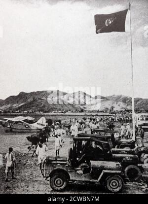 Photographie en noir et blanc de la guerre de Corée (1950-1953); un drapeau aux couleurs de l'ONU survole un aérodrome. Banque D'Images