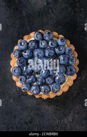 Tartelette au citron avec des bleuets frais sur fond noir. Vue d'en haut. Avec un espace réservé au texte Banque D'Images