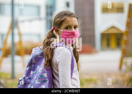 Écolière portant un tissu de protection réutilisable masque facial allant à l'école. Éducation scolaire pendant la pandémie du coronavirus. Sécurité, distanciation sociale Banque D'Images