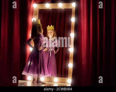 Petite actrice mignonne. Enfant fille en costume de princesse sur le fond de scènes théâtrales et de miroirs. Banque D'Images