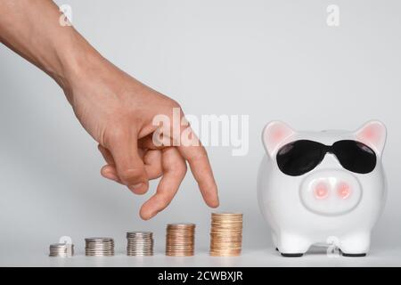 investir dans un sac de financement pour une vie future bonne. main tenant une banque de piggy pièces de fond blanc Banque D'Images