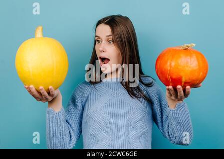 Photo horizontale d'une jeune femme impressionnée surprise regarde étonnamment la citrouille d'orange, retient le souffle de l'émerveillement Banque D'Images