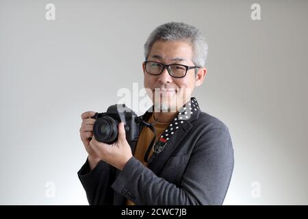 L'homme asiatique dans une ambiance décontractée et élégante debout sur fond blanc. Banque D'Images