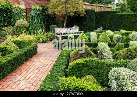 Parterre de jardin à nœud avec zone de couverture avec chemin de carrelage, un joli jardin clos et soigné avec banc de jardin siège Surrey UK Banque D'Images