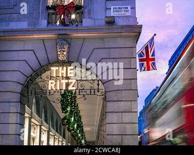 The Ritz Hotel at Christmas, le crépuscule lumières la saison de fête, le soir lumières le signe «le Ritz» illuminé et un drapeau Union Jack affiché, le bus rouge de Londres passant avec le flou de vitesse. Arlington Street Piccadilly Londres, Royaume-Uni Banque D'Images