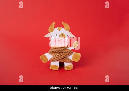 Vache artisanale en carton, Comment faire un taureau ou un boeuf à la maison. Projet d'art pour enfants. Bricolage concept.figurine jouet sur rouge. Instructions détaillées sur la photo. St Banque D'Images