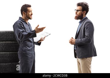 Mécanicien avec une pile de pneus parlant à un barbu homme isolé sur fond blanc Banque D'Images