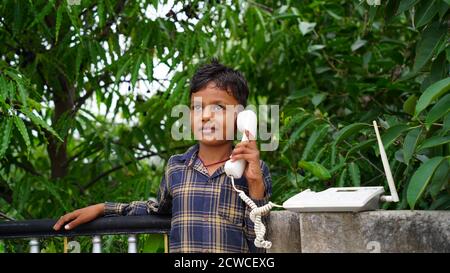 Adorable petit garçon indien parlant son père avec un téléphone sans fil. Banque D'Images