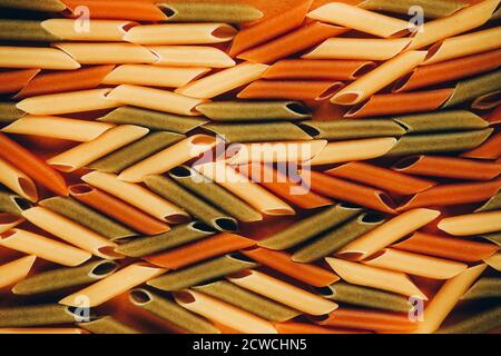 Cadre composé de pâtes vertes, jaunes et rouges de penne colorées naturellement avec de la tomate et des épinards. Concept des produits non périssables. Banque D'Images