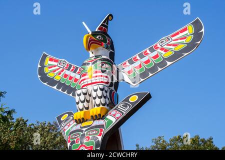 Mât de totem canadien sculpté en bois coloré montrant l'aigle contre le bleu ciel Banque D'Images